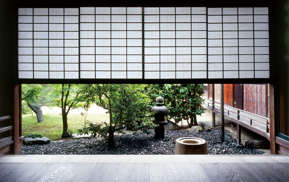 The teahouse garden is picture-framed with the hanging paper screen from above and the wooden veranda from below. The stone hand basin is seen only with its circular hole on top; the rest is hidden beneath the veranda.