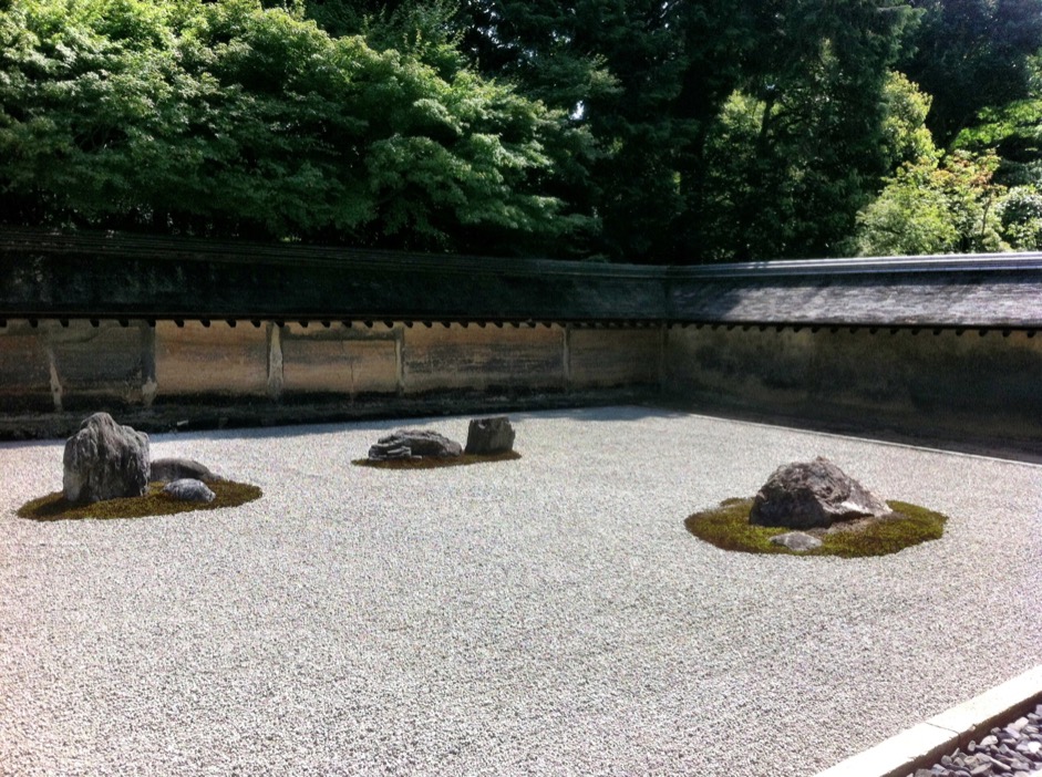 The garden's ground is covered with gravels on which the three rocks are placed on the left, a pair of rocks on the middle-left, and another group of rocks on the right.